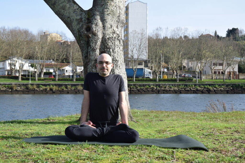 Bernardo Gamallo sentado en postura de meditación junto al río en Pontevedra